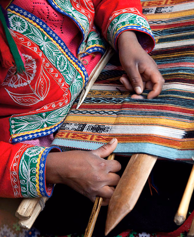 Luxury Peru Tours - A woman's hand weaving traditional, colourful wool fabric in Peru