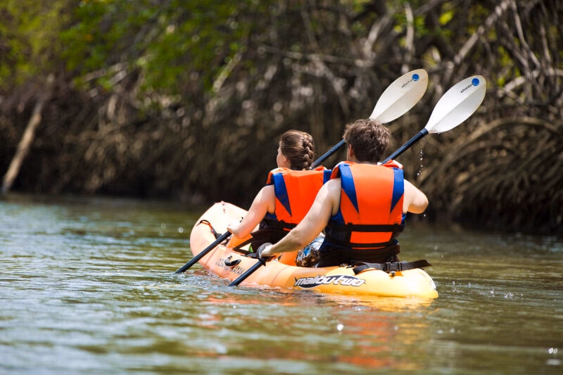 Luxury Costa Rica tours - two people in life vests paddling a kayak on a still river in a rainforest