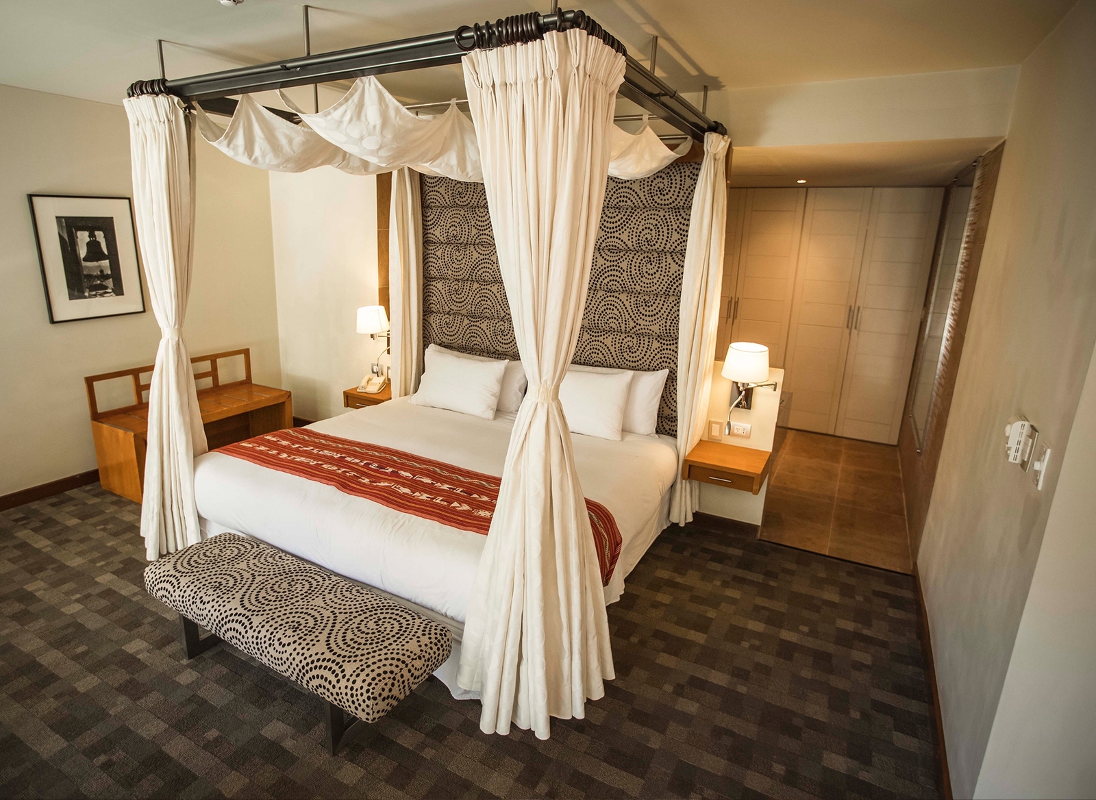 Elegant bedroom with a four-poster bed, patterned accents, and soft lighting.