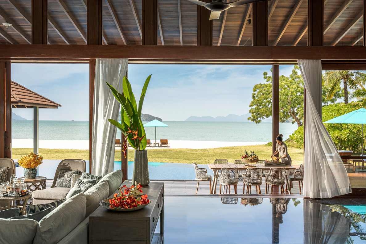 Inside a beachfront villa looking out to a private infinity pool, white sand beach and blue ocean waters.