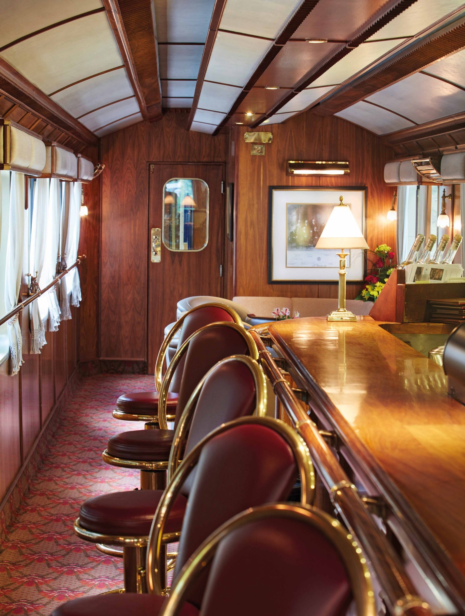 Luxurious train carriage interior with wooden panels and comfortable seating areas.