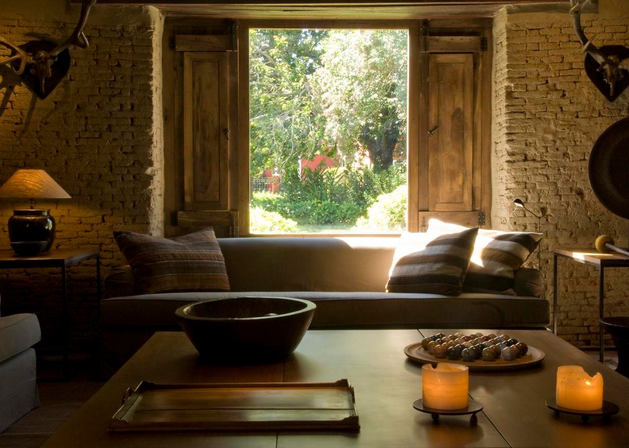 Cozy interior room with a couch, cushions, and view of a green garden through an open window.
