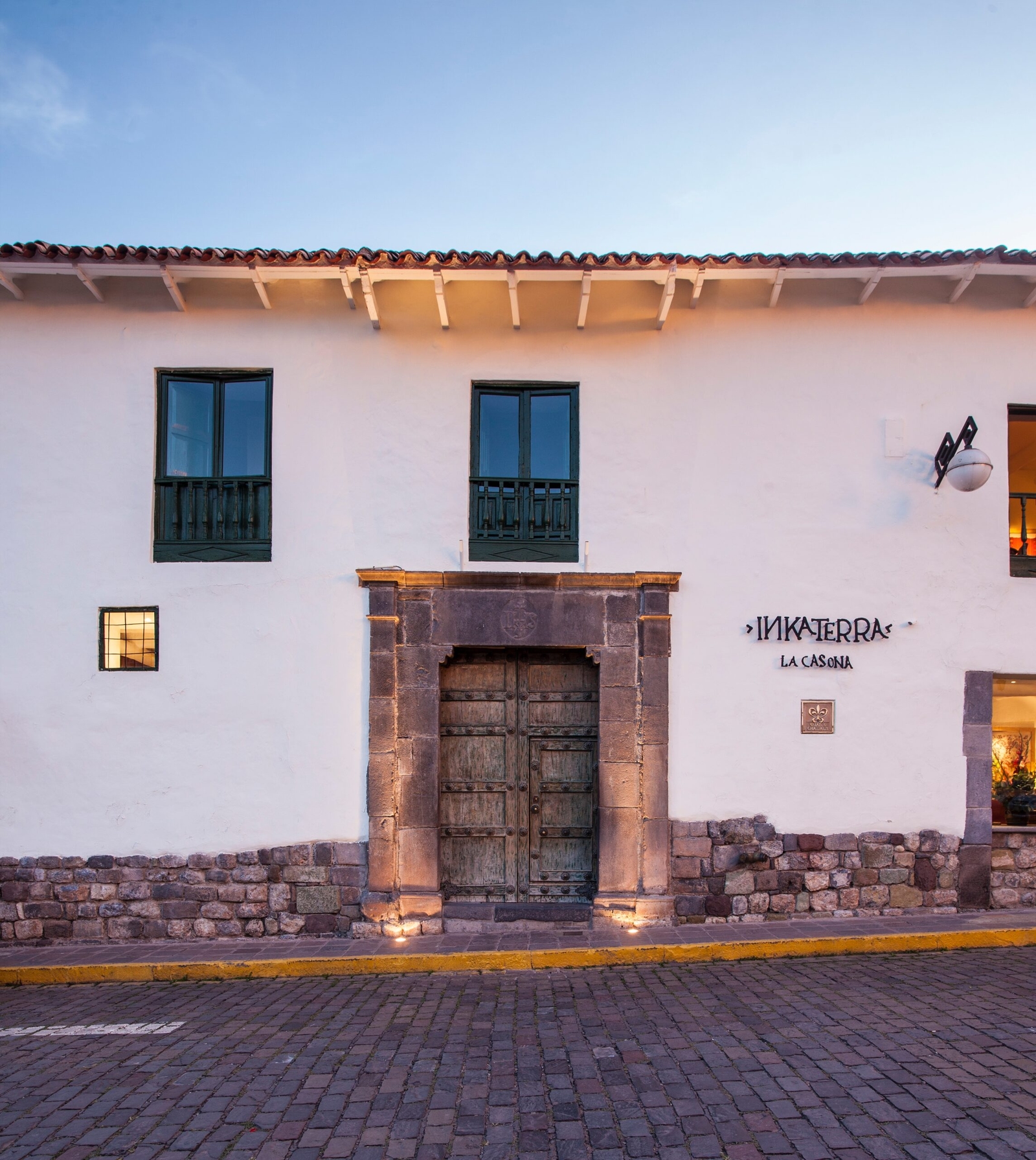 Colonial building facade with a wooden door and sign reading "Inkaterra La Casona."