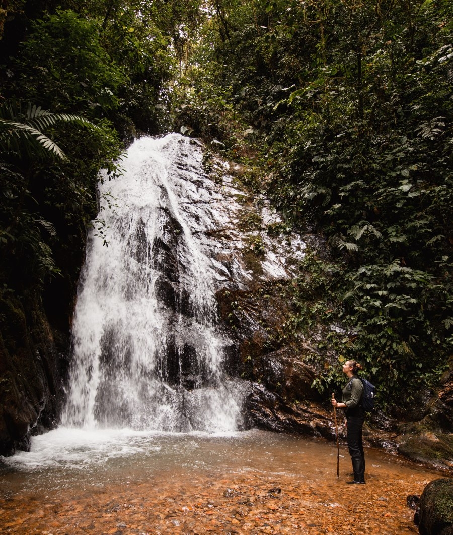 A person standing at the base of a waterfall.