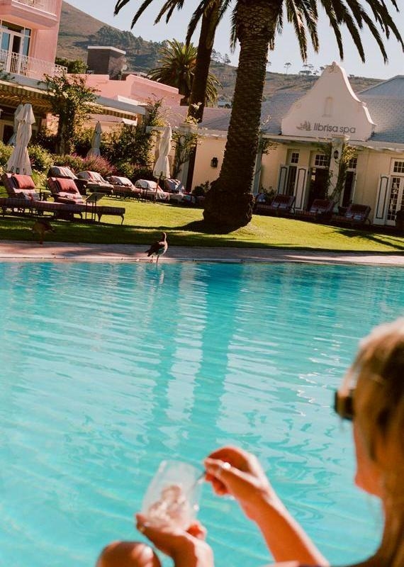Outdoor swimming pool looking towards a white building labeled Librisa Spa with pink hotel buildings in the background.