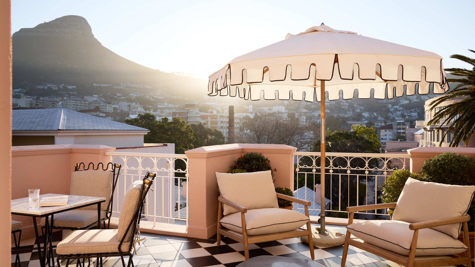 Rooftop terrace with checkered floors, white umbrella, and lounge chairs with Table Mountain in the background.