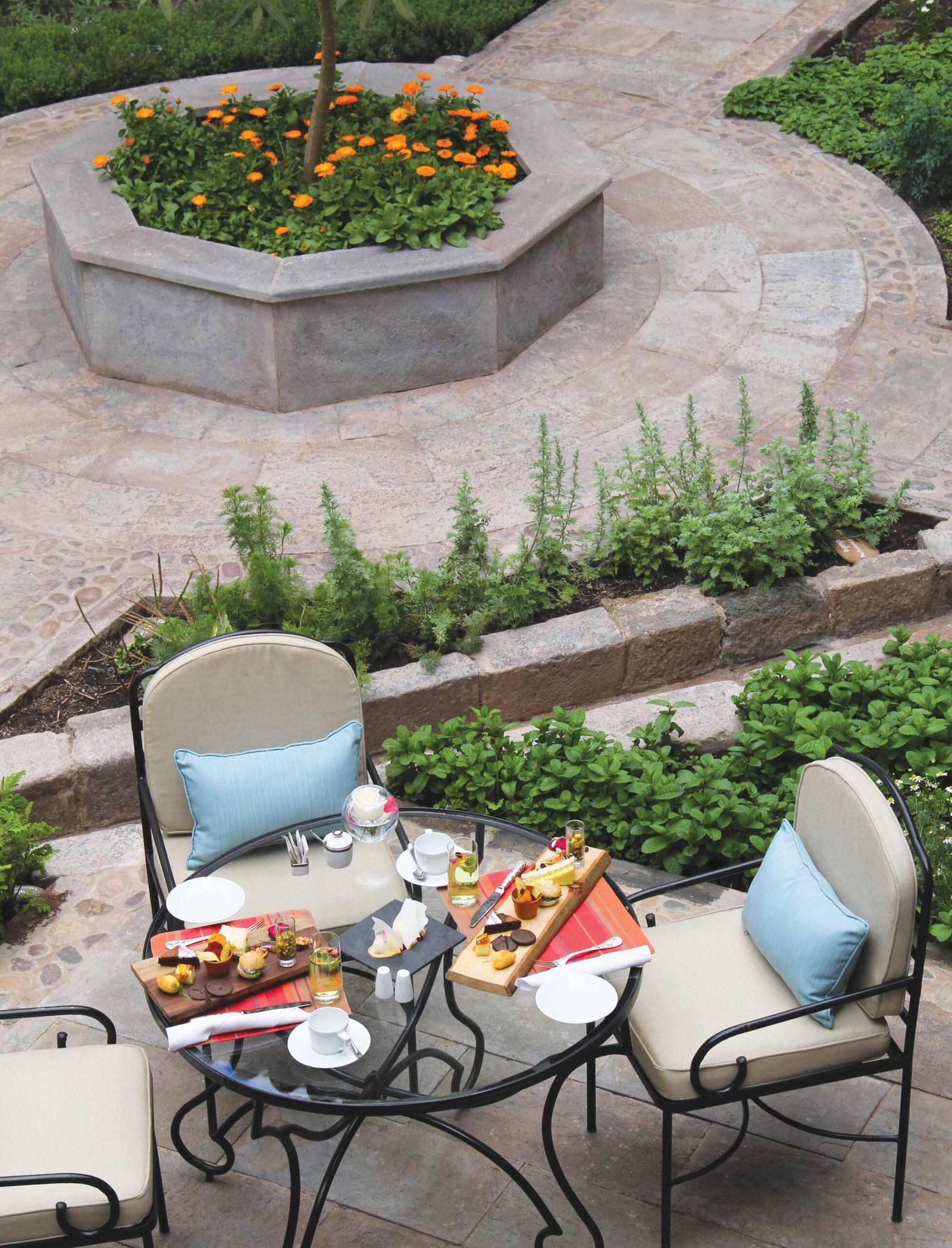 Outdoor patio table with breakfast setup, overlooking a landscaped area with flowers.