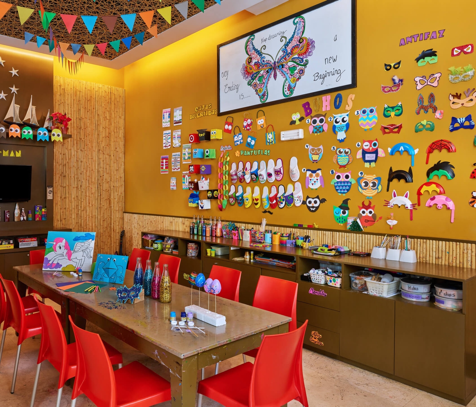 A room featuring a table and chairs, with text on the wall. The furniture includes a desk and various other indoor elements.