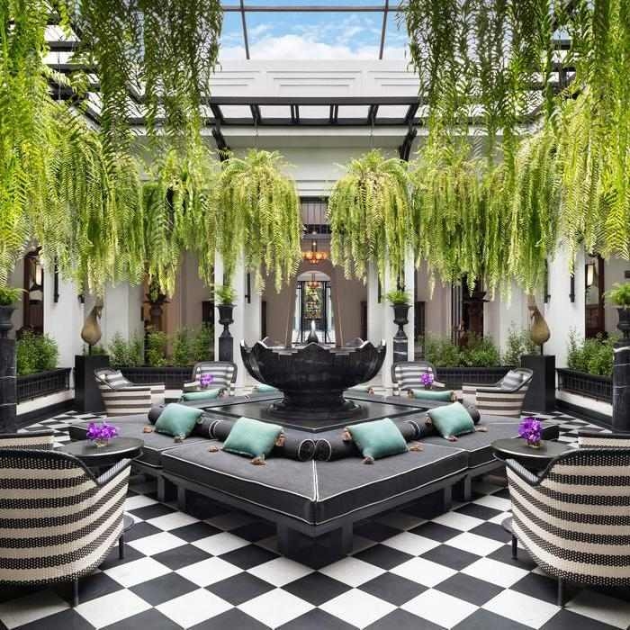 The Siam courtyard with checkered flooring, a central fountain, and large ferns hanging from the ceiling.