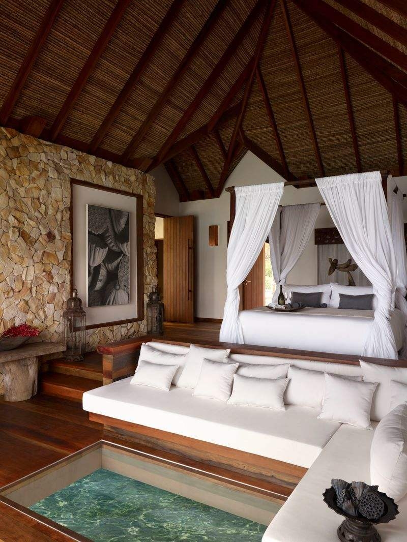 High-ceilinged bedroom with a white canopy bed and a glass floor section showing the water below.