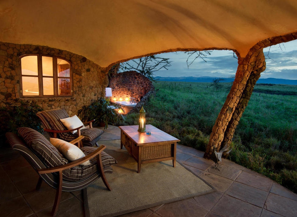 A patio at dusk with striped chairs, a lantern, and a view of the horizon under a blue twilight sky.