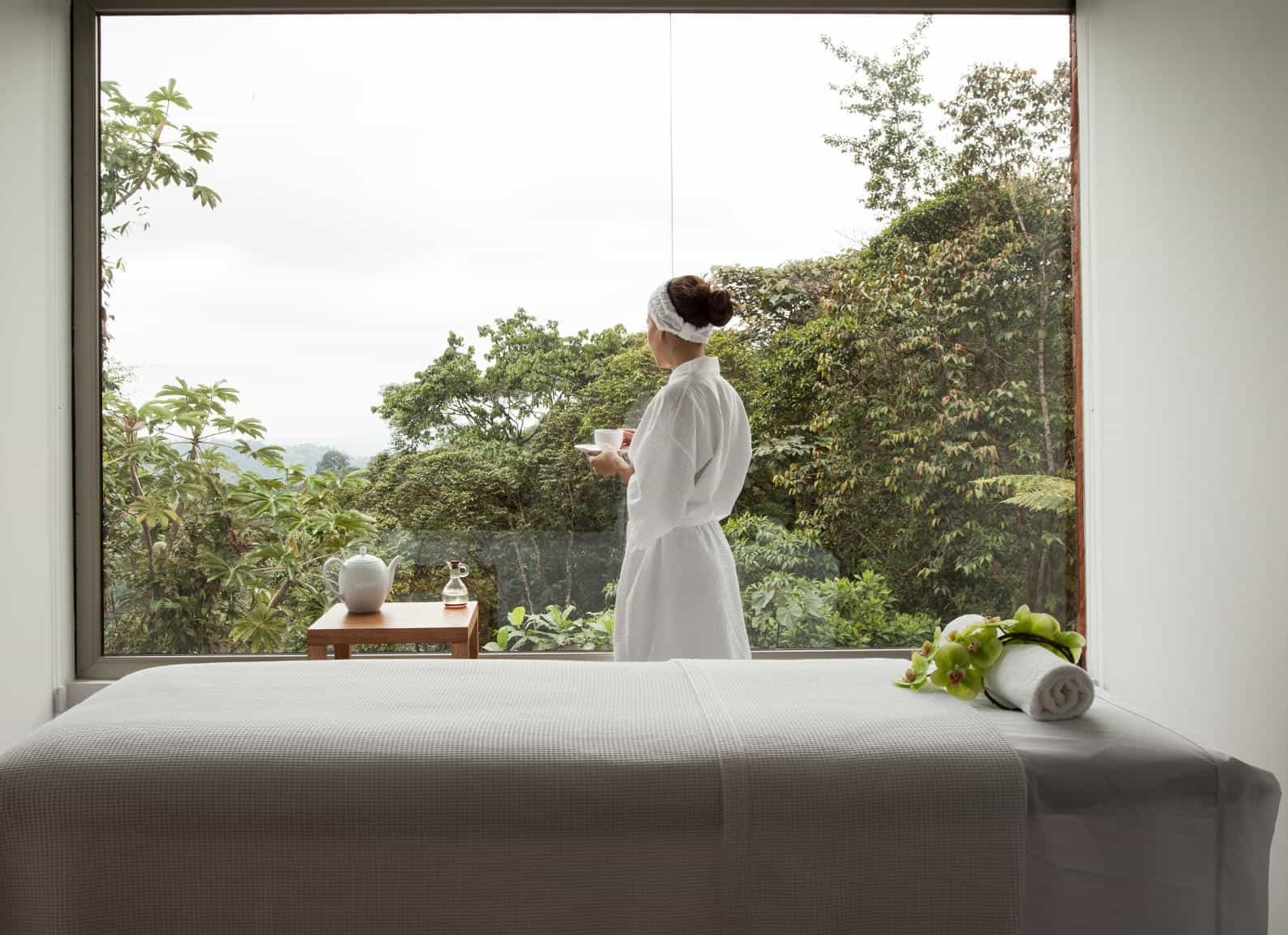 A person overlooking the forest with a massage table in the foreground.