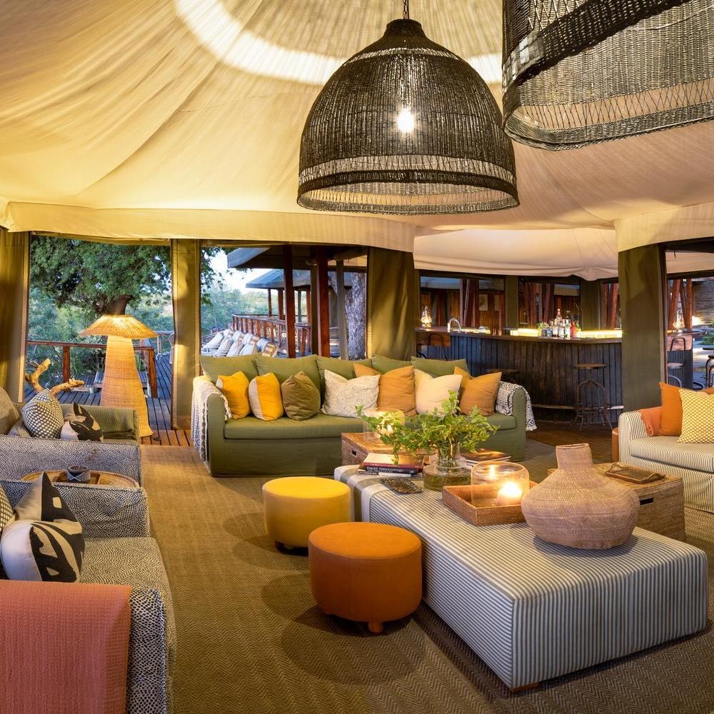 People sitting around a fire pit on an outdoor deck at sunset at Simbavati Hilltop Lodge.