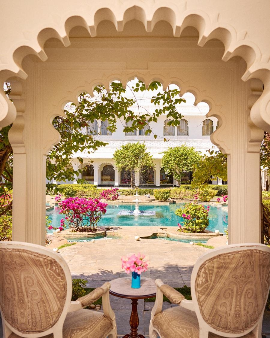 Two chairs beneath an ornate arch overlooking the Taj Lake Palace's beautiful courtyard area.