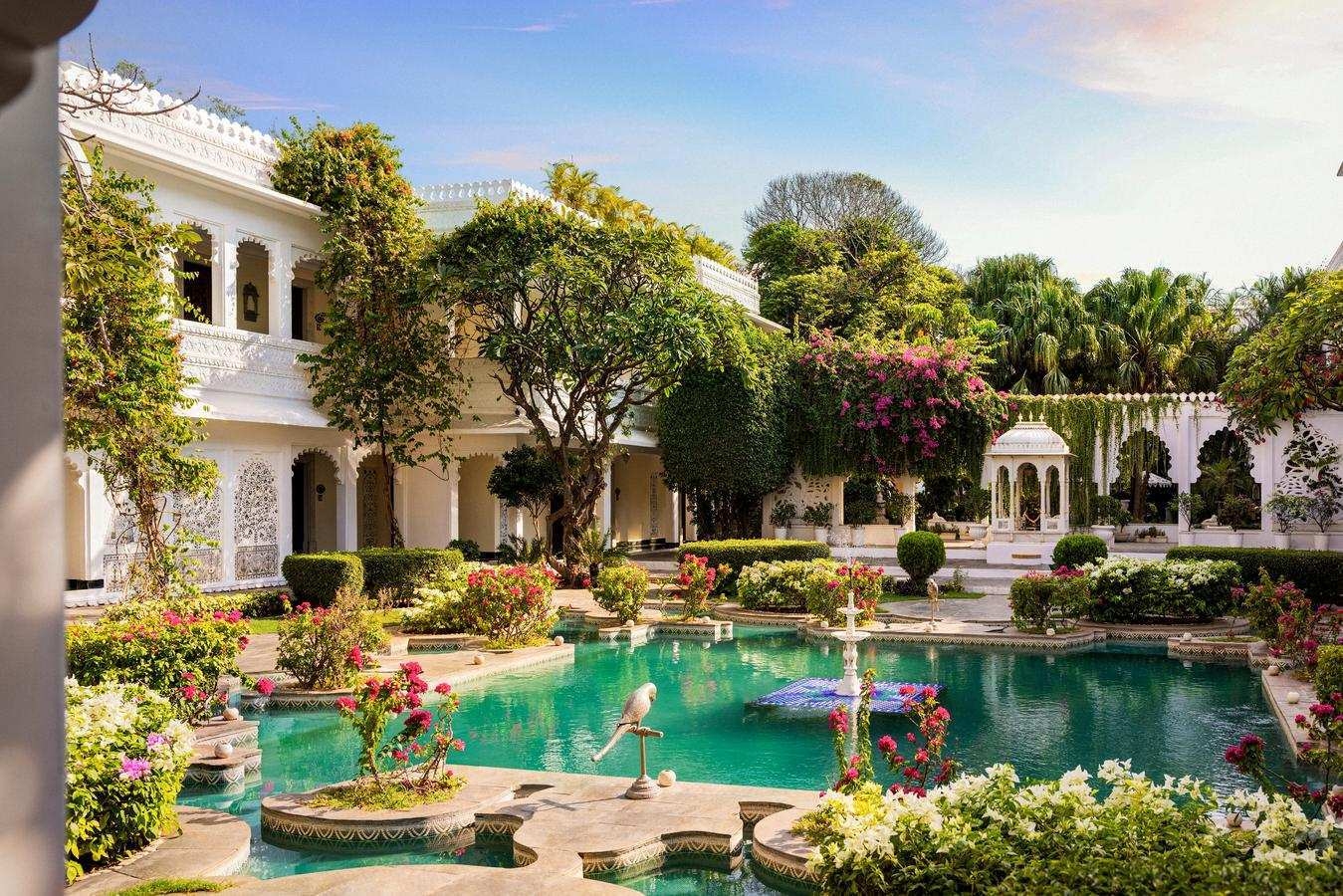 The beautifully manicured courtyard area of Taj Lake Palace featuring lush trees, flowers and fountains.