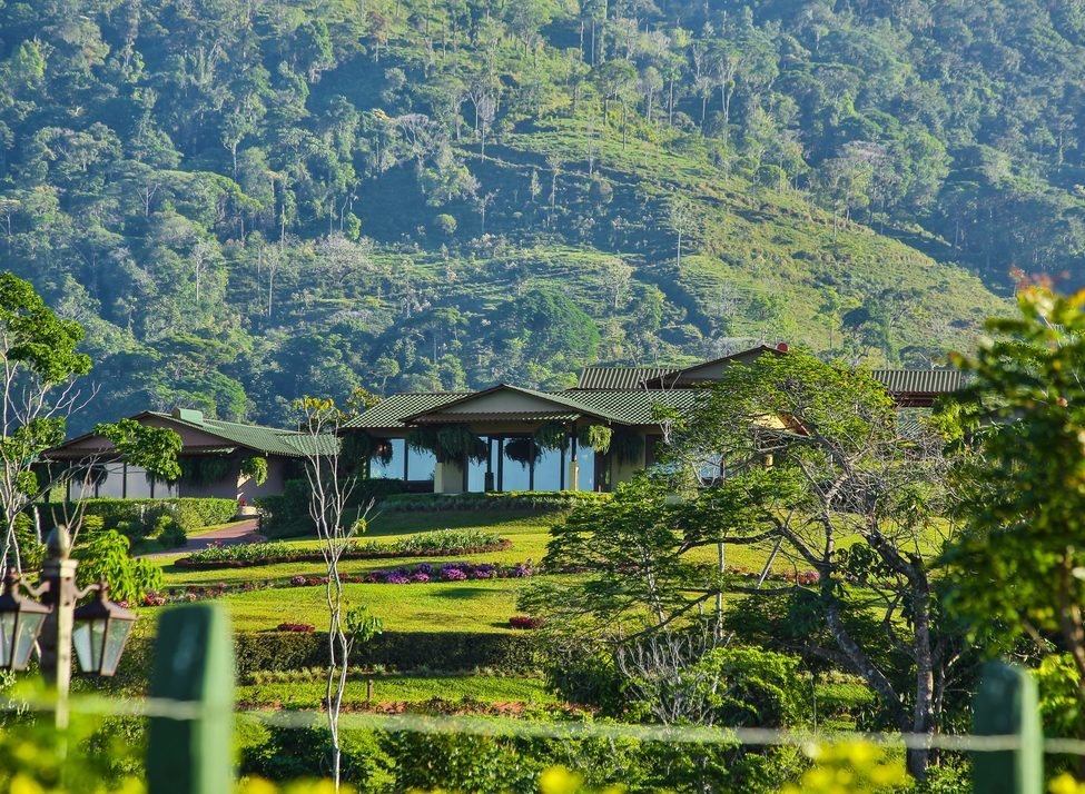 Hacienda AltaGracia on a terraced hillside surrounded by dense tropical forest and mountains.