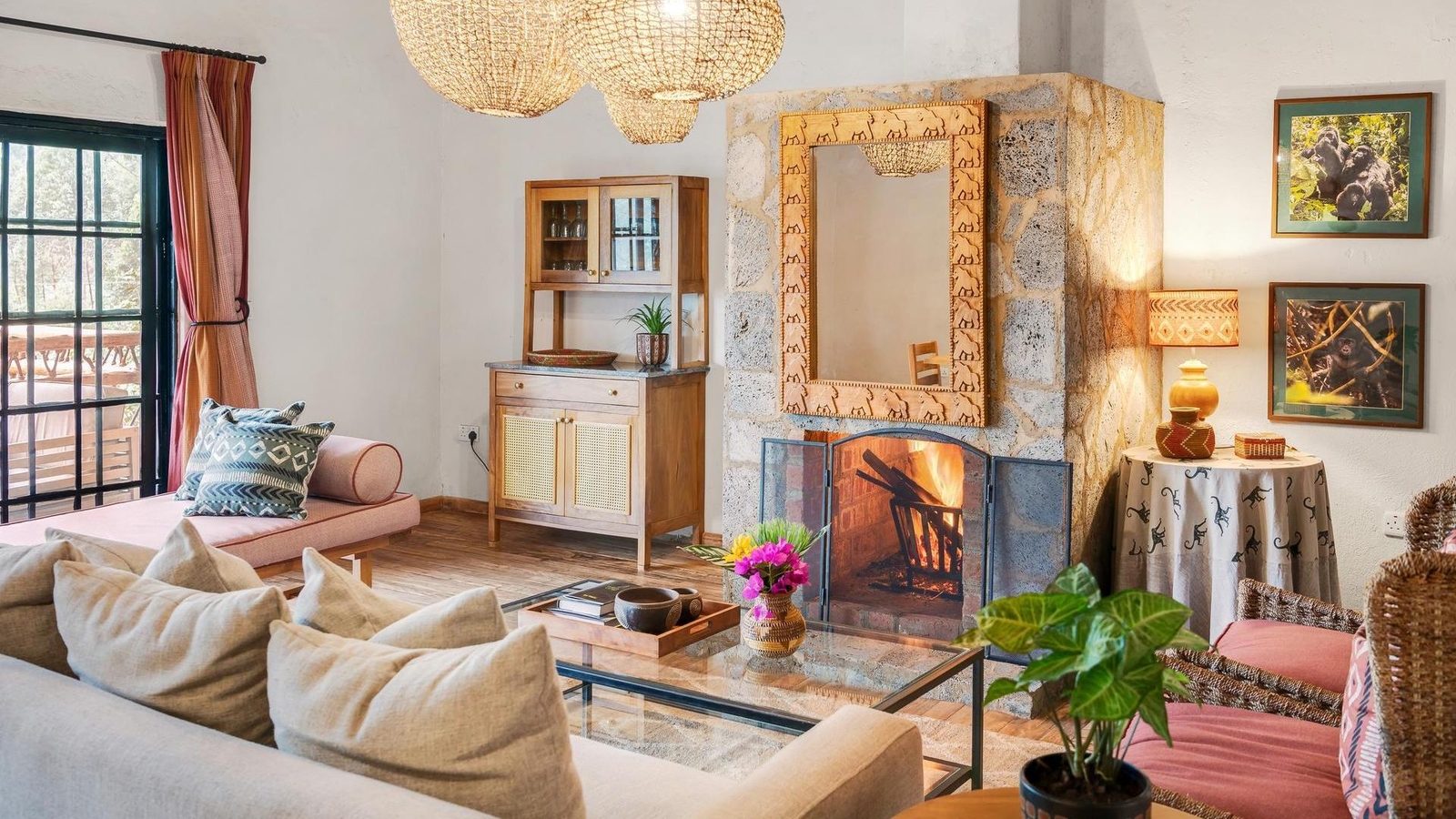 Lounge at Mahogany Springs uganda featuring a lit fireplace in a stone wall, seating, and framed gorilla photos.