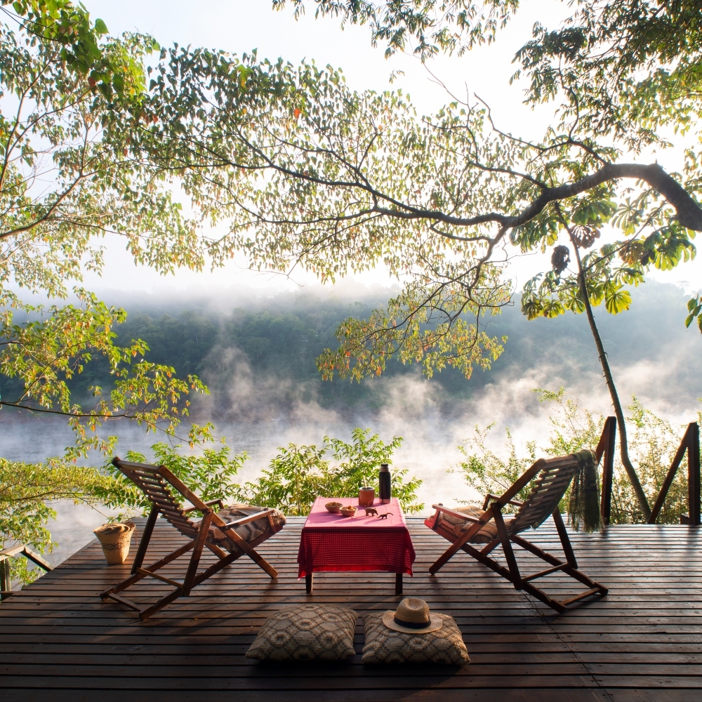 Two chairs on an outdoor deck overlooking a mist-shrouded river.