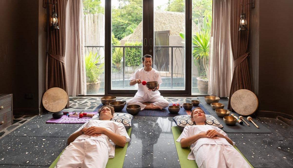 A couple participating in a singing bowls ritual alongside an expert.