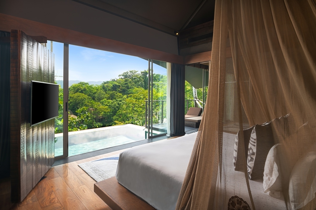 The bedroom area of one of Keemala's villas overlooking a pool and the trees beyond.