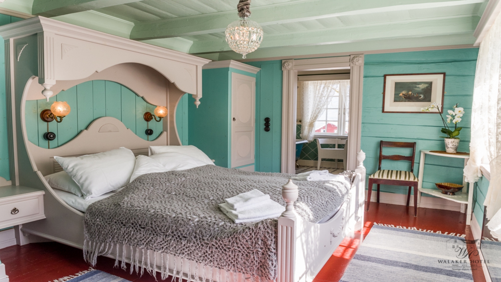 Cozy bedroom with a white vintage bed, mint green walls, and a crystal chandelier.
