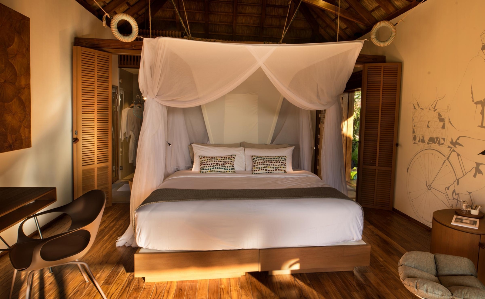 Tropical bedroom interior with a canopy bed, mosquito netting, wooden floors, and soft evening lighting.