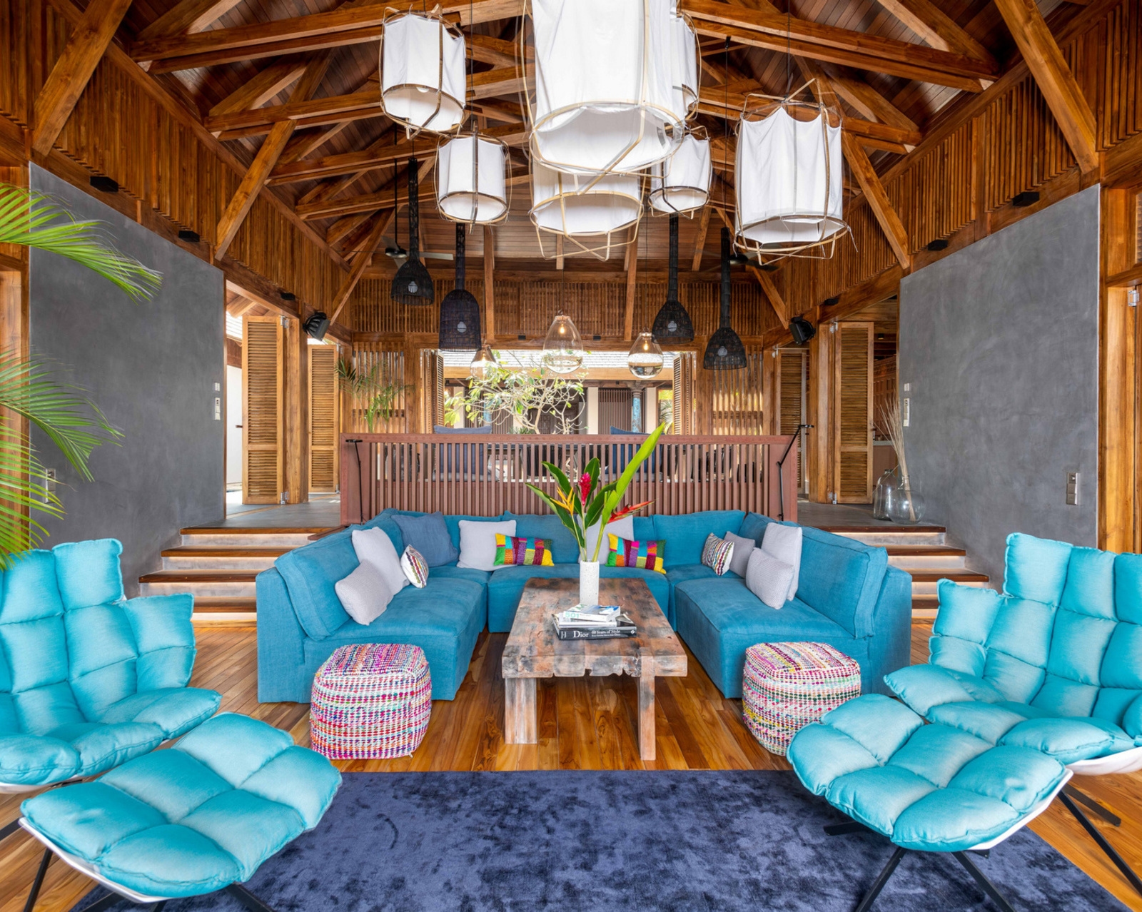 Interior lounge with blue sofas, bright cushions, and unique fabric lanterns hanging from a wooden ceiling.