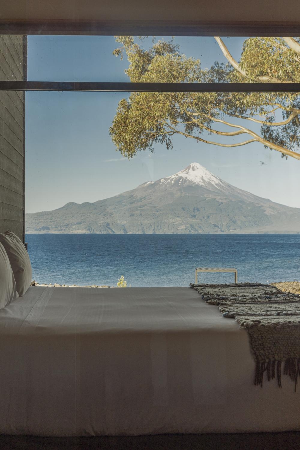 The bedroom of one of Hotel AWA's rooms overlooking the lake and volcano.