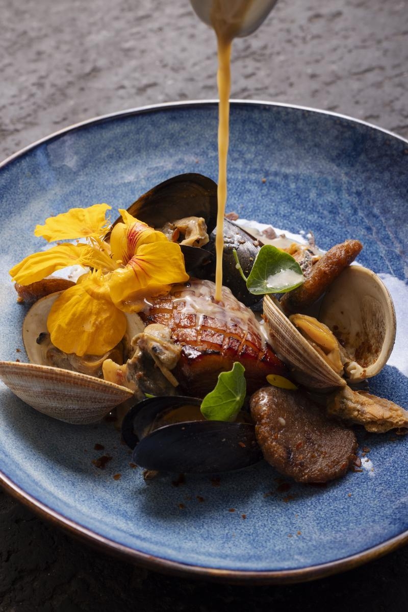 A masterfully prepared meal at Hotel AWA with sauce being poured onto the dish.