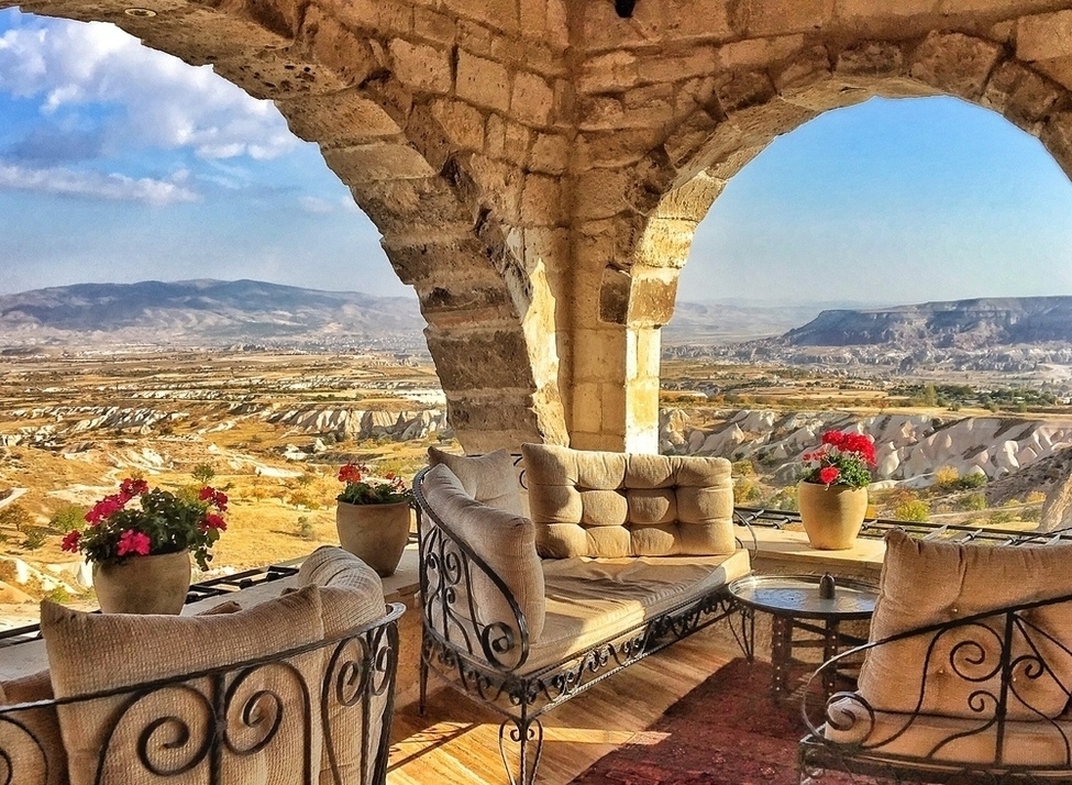 Stone arch terrace with plush seating and flowers overlooking the valley at the Museum Hotel in Turkey.