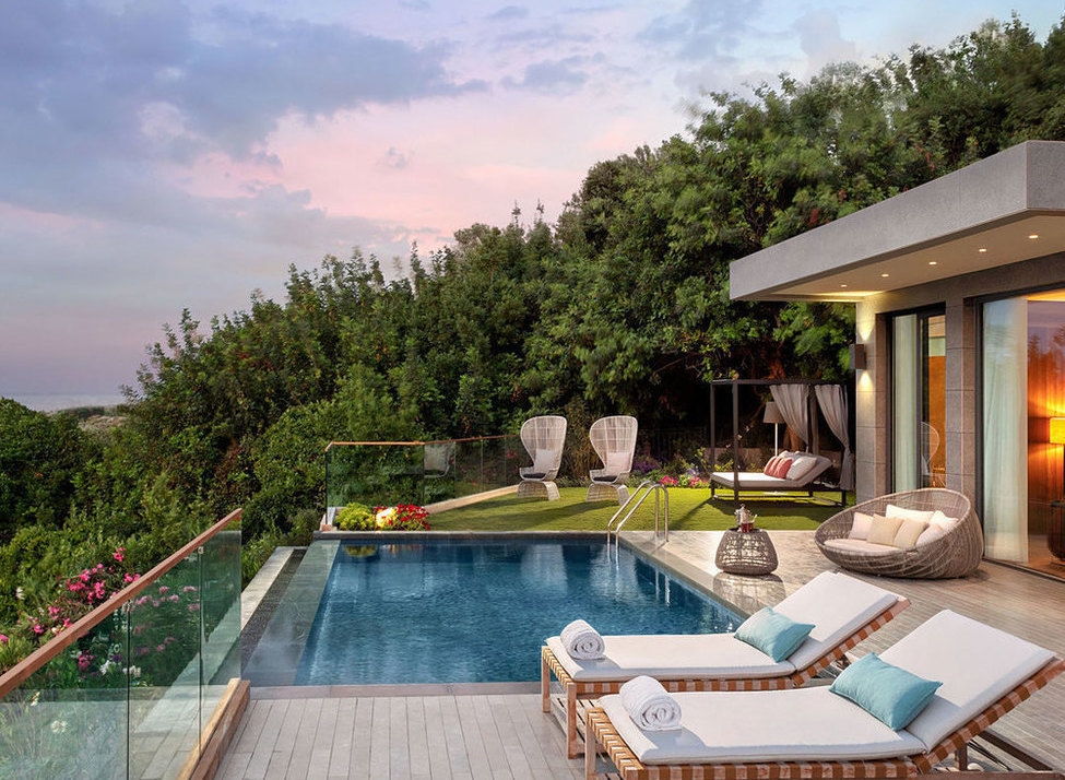 Luxury terrace with a private swimming pool, sun loungers, and modern outdoor furniture overlooking a lush forest.