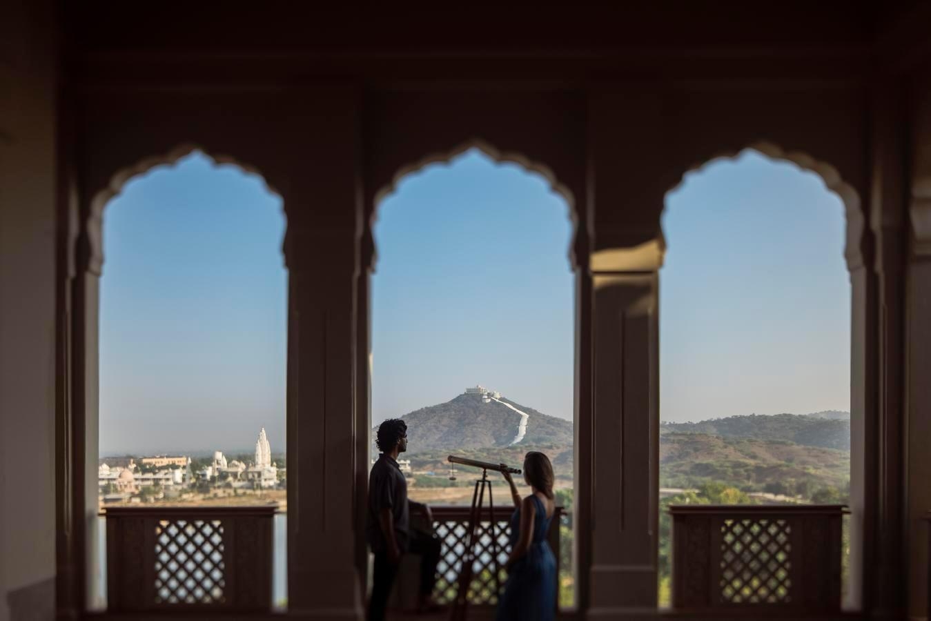 Two people at the viewing gallery at Six Senses Fort Barwara, featuring a telescope.