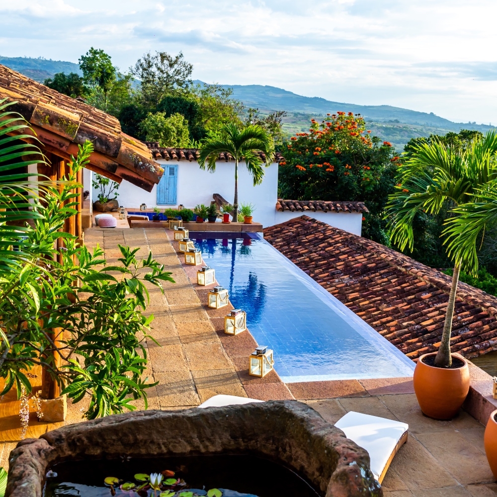 Terracotta-tiled patio with an infinity pool overlooking a scenic landscape at dusk.