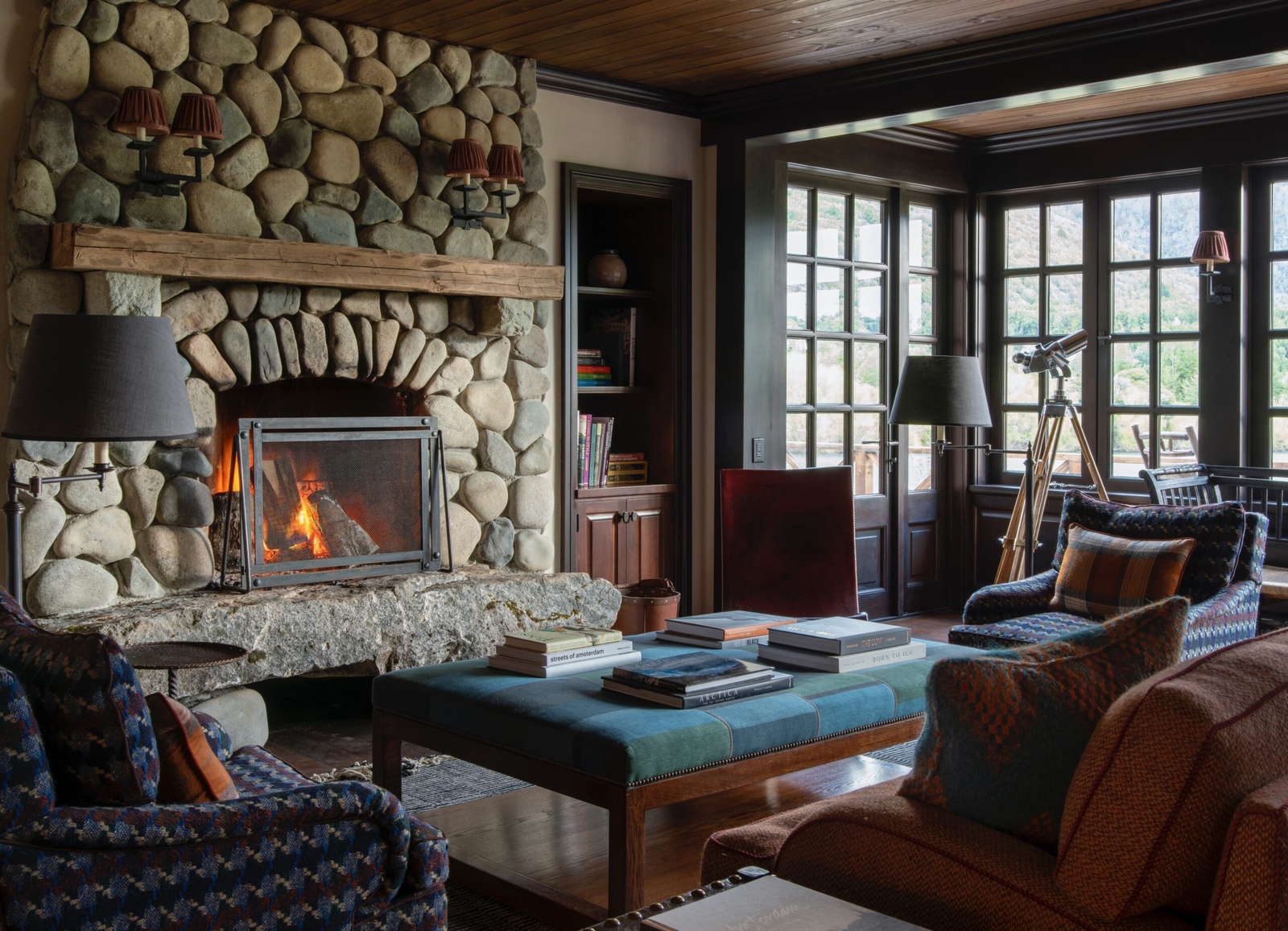 Cozy room with stone fireplace, reading area, and telescope by window.