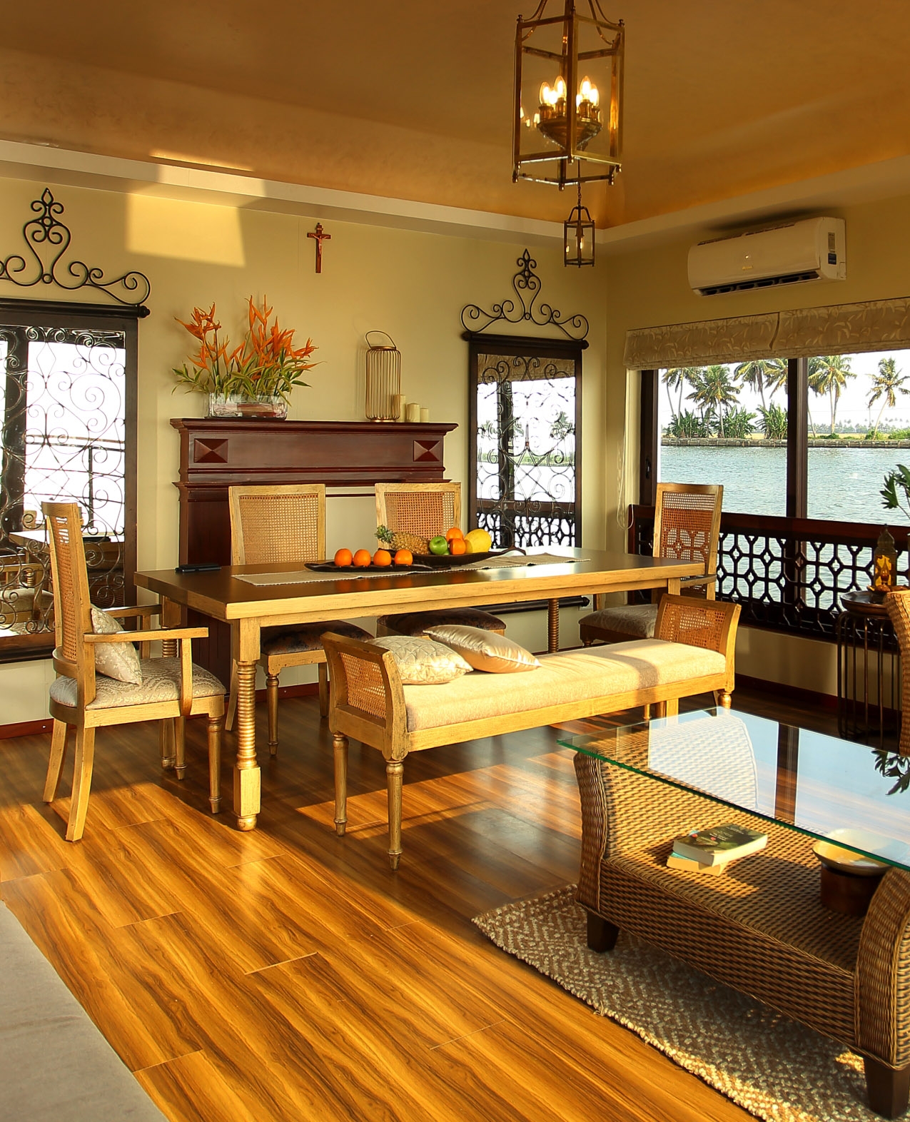 Elegant dining room with wooden furniture, ornate metalwork, and a waterfront view.