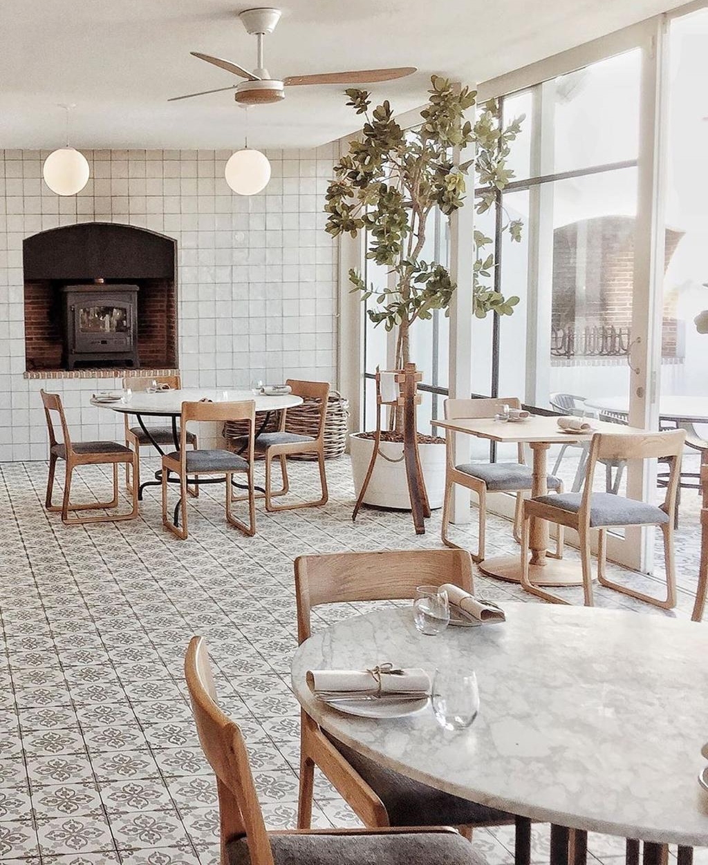 Elegant dining area with patterned floor tiles, wooden tables, chairs, and a fireplace.