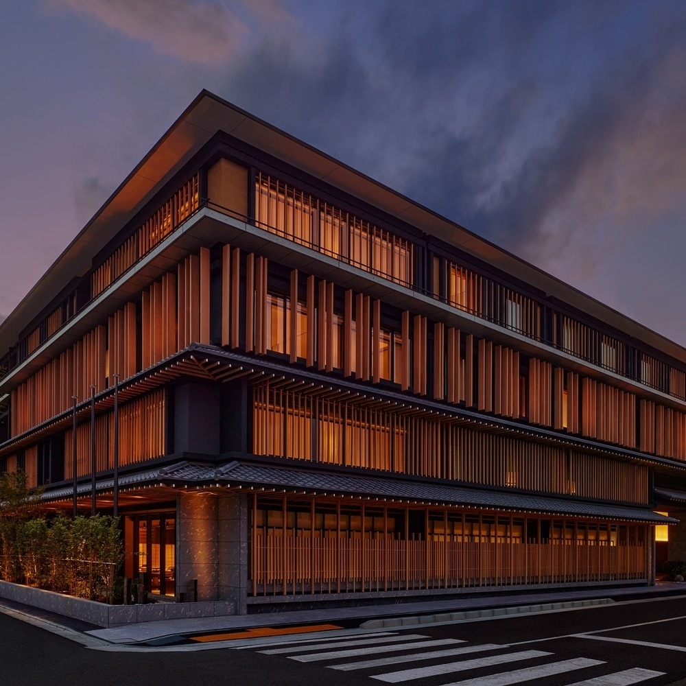 Modern building with wooden slat exterior, illuminated at twilight against a dusky sky.