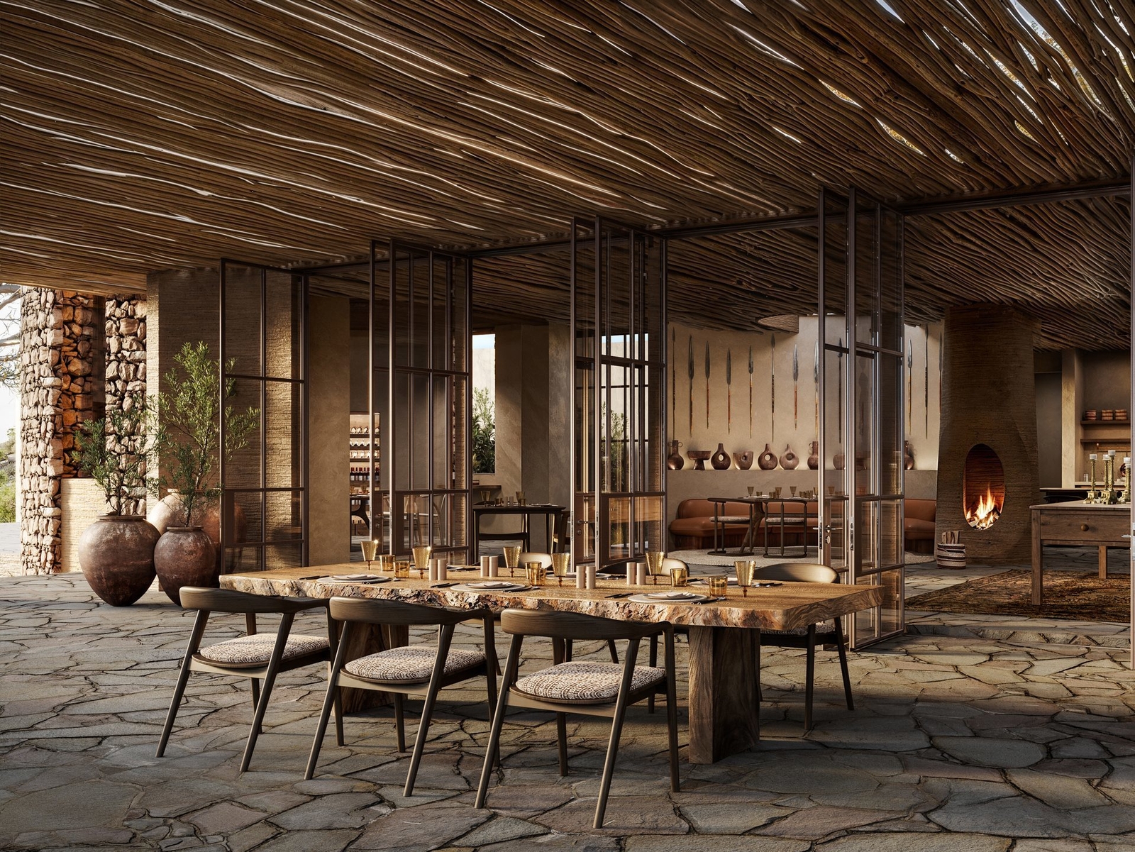 Rustic dining room with wooden table, stone flooring, and an open fireplace.