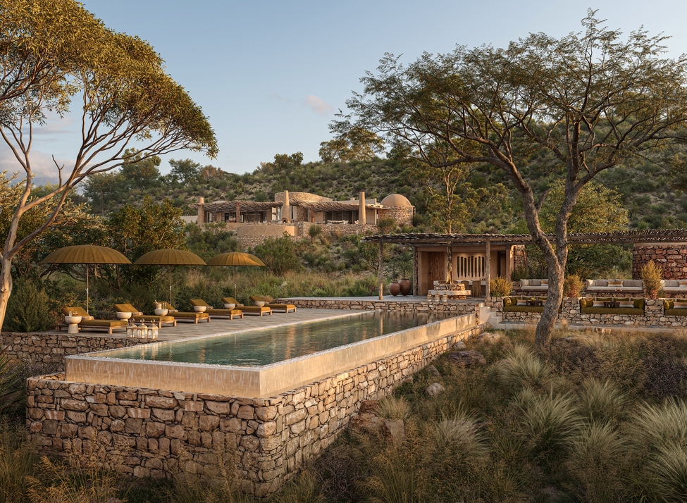 A rectangular stone infinity pool with yellow umbrellas and lounge chairs at Suyian Lodge, surrounded by trees and hills.