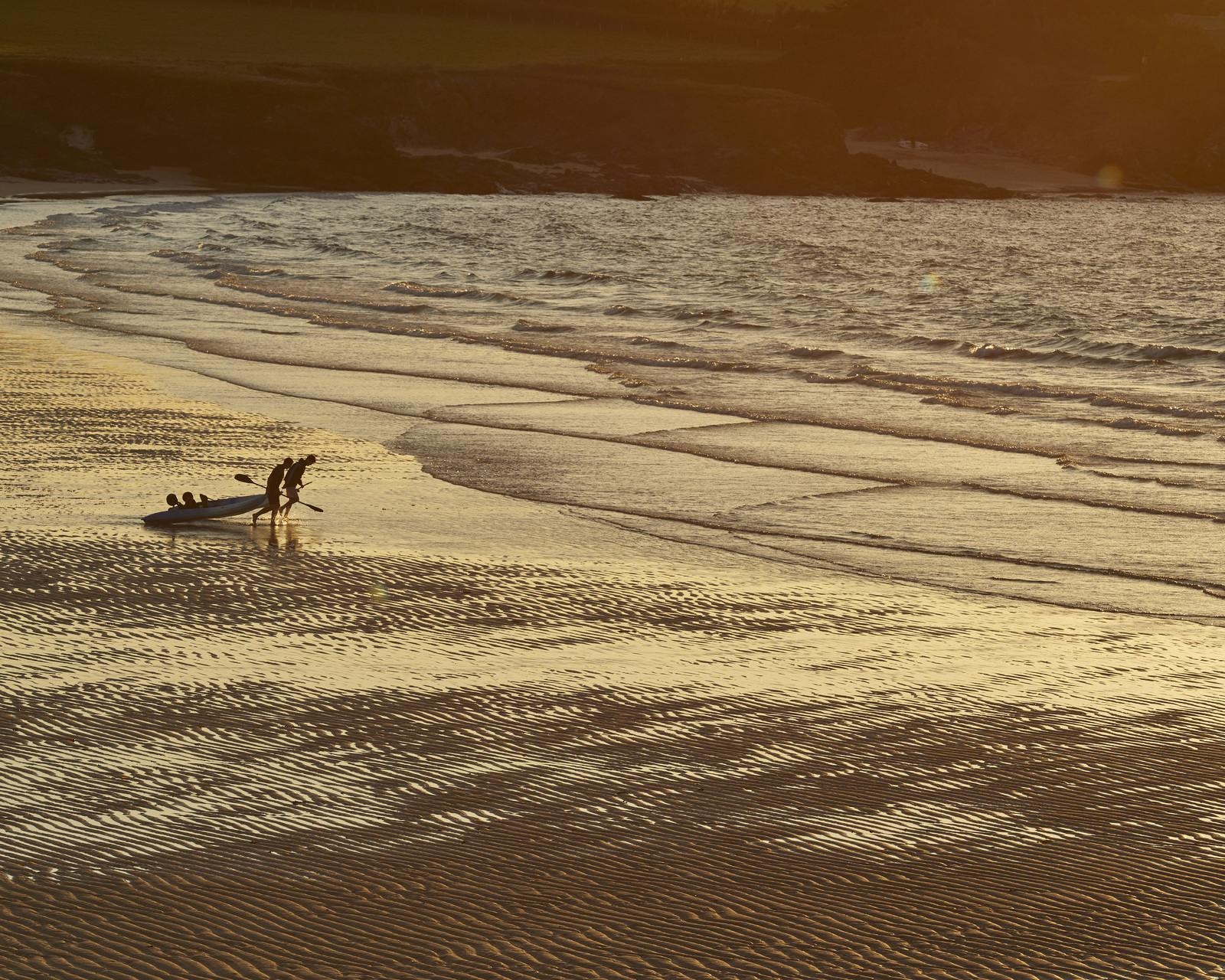 Surfers on the beach at sunrise at The Pig at Harlyn Bay