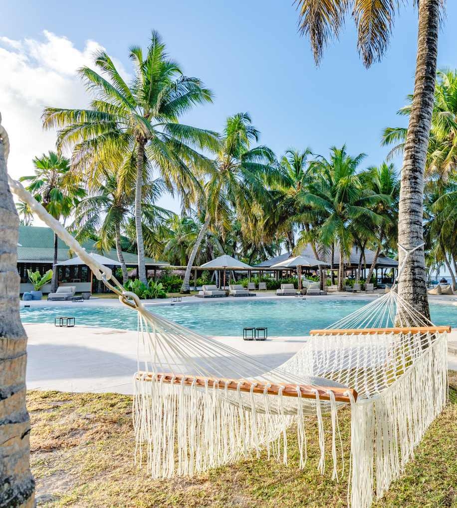 The main pool area on Alphonse Island, featuring a hammock between palm trees in the foreground.