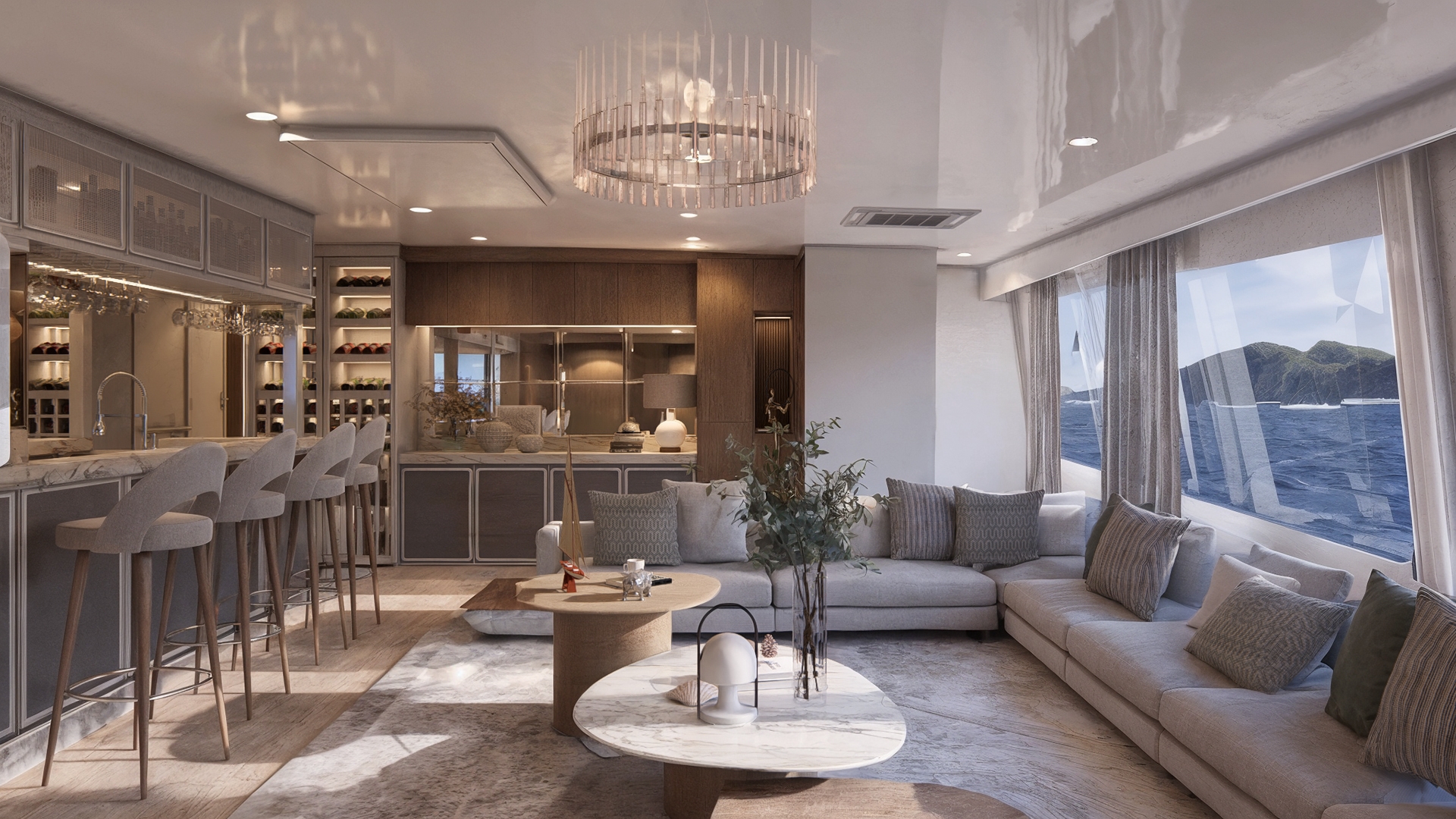 An indoor bar with big windows looking out to sea and a shoreline with green mountains. Inside are grey banquette seats and low cocktail tables under the windows on the right. On the left is a bar with tall grey chairs. There is a chandelier overhead.