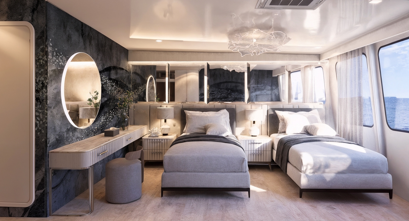 A bedroom with windows with views out to sea with a see-through curtain partially covering them. Inside are two single beds with grey and white sheets and pillows, a crystal chandelier, white carpeting and a round vanity mirror along a dark grey wall.