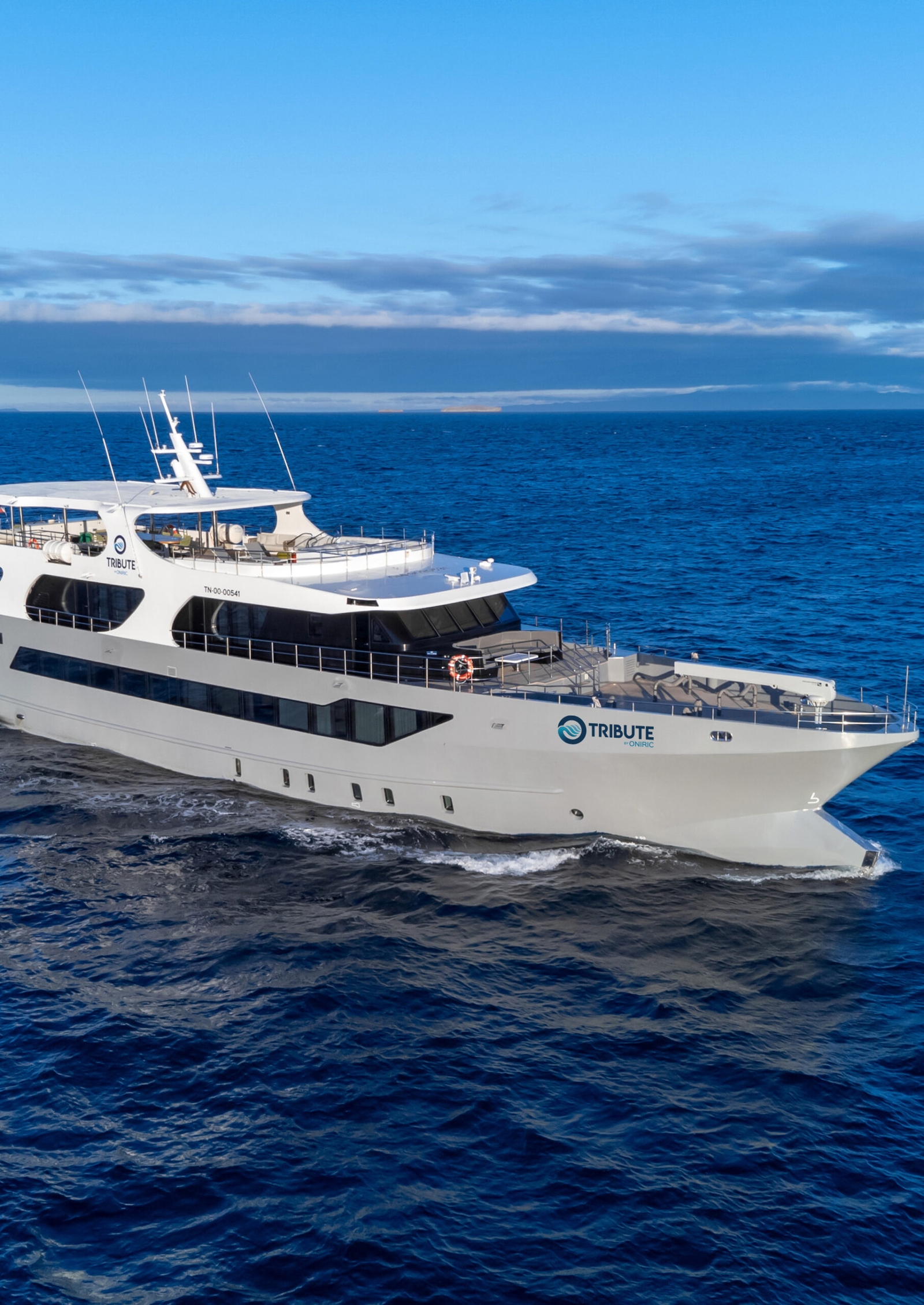 Yacht sailing on dark blue water with a light blue sky in the background.