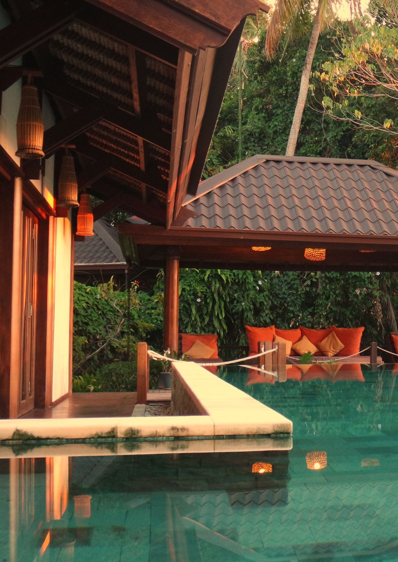 Exterior of a pool with covered lounge area and trees in the background.