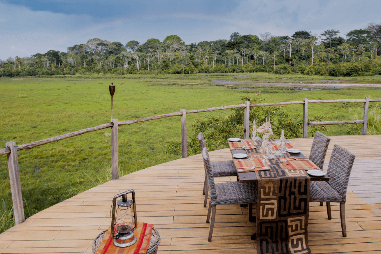 A dining table set for four on a wooden platform overlooking the Lango baï