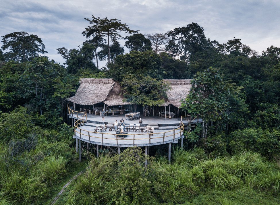 Wide view of Lango Lodge's round wooden viewing platform and thatched-roof buildings