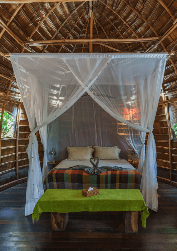 Canopy bed with mosquito net and two towels folded to look like swans