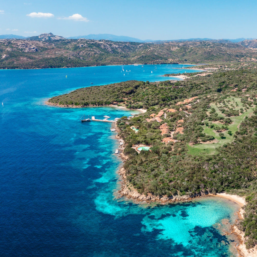 Aerial view of the blue and turquoise sea and the property along the green coast.