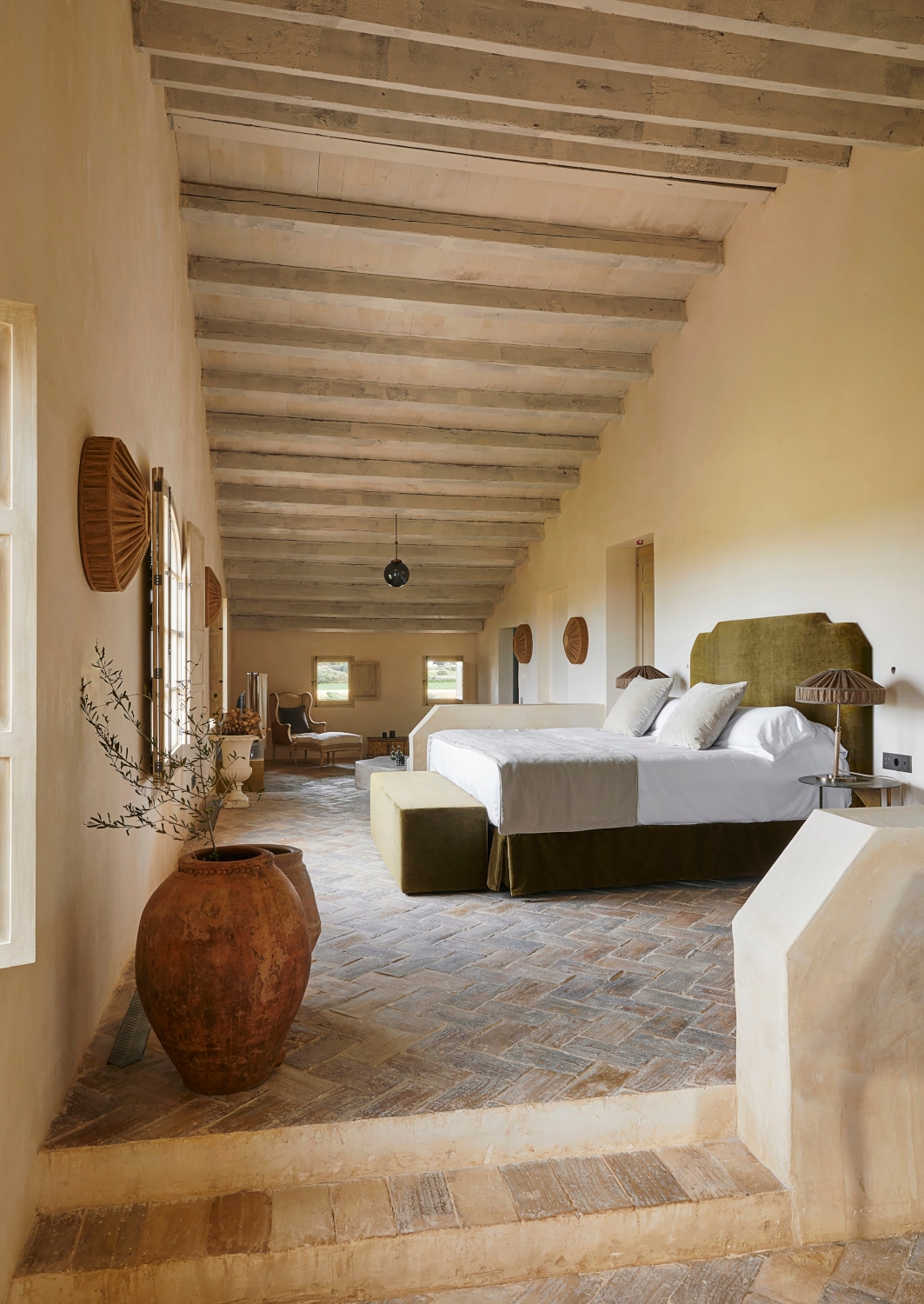 Expansive bedroom suite at Son Vell in Balearic Islands Spain with terracotta floors and rustic wood-beamed ceiling.